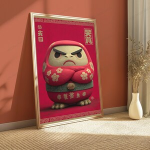 Peut inclure: Une affiche verticale encadr&eacute;e repr&eacute;sentant une poup&eacute;e Daruma rouge avec un visage cr&egrave;me, des sourcils noirs &eacute;pais et une expression s&eacute;v&egrave;re. La poup&eacute;e pr&eacute;sente des motifs floraux blancs sur les bras, une ceinture verte et des caract&egrave;res asiatiques.