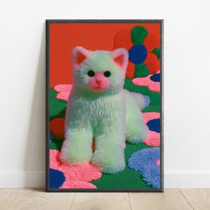 K&ouml;nnte beinhalten: Ein Pl&uuml;schkatzenspielzeug mit hellgr&uuml;nem Fell, rosa Ohren und einer rosa Nase, das auf einem Teppich mit buntem Blumenmuster mit gro&szlig;en rosa, blauen und gr&uuml;nen Bl&uuml;tenbl&auml;ttern vor einem leuchtend orangefarbenen Hintergrund steht, in einem schwarzen Rahmen.