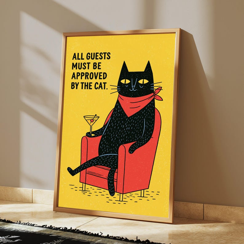 May include: A framed rectangular wall art print featuring a yellow background with a black cat wearing a red bandana, sitting in a red armchair, holding a martini glass, and the text: ALL GUESTS MUST BE APPROVED BY THE CAT.