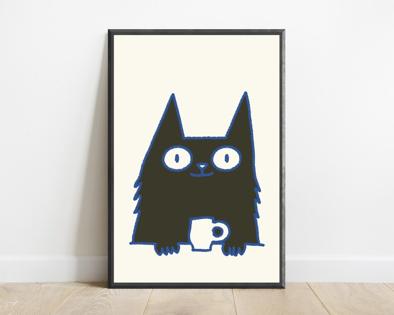 May include: A framed wall art print featuring a black cat illustration with wide white eyes and a blue outline. The cat is holding a small white mug with both paws against a cream-colored background. The frame is thin and black.