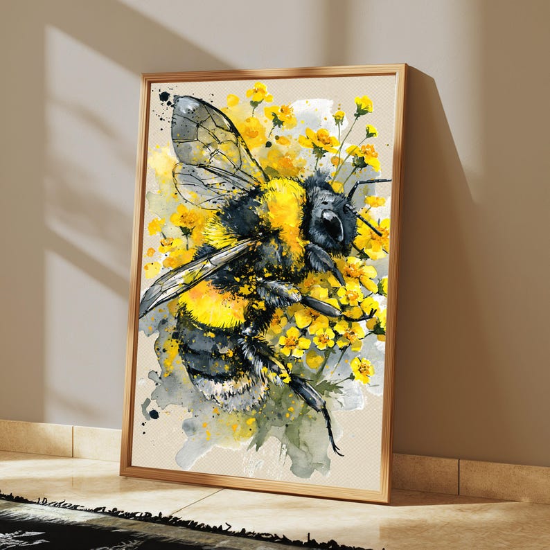 May include: A framed wall art print featuring a watercolor illustration of a fuzzy bumblebee with black and yellow stripes, surrounded by small yellow flowers. The artwork uses splattered paint effects in shades of gray, black, and yellow.