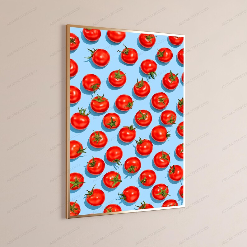 May include: A rectangular wall art print in a thin gold frame featuring a repeating pattern of bright red tomatoes on a light blue background. The tomatoes are arranged in a grid-like formation, each showing green stems and a smooth, round surface.