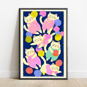 May include: A framed art print featuring a dark blue background with multiple cream-colored cats wearing pink, green, and yellow overalls. The cats are depicted playing with various colorful yarn balls in shades of pink, yellow, orange, and blue.