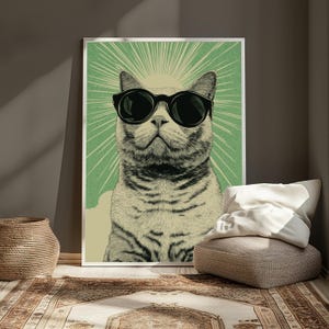 Puede incluir: Una impresi&oacute;n de arte mural vertical que presenta una ilustraci&oacute;n estilizada de un gato con gafas de sol negras grandes. El gato est&aacute; centrado sobre un fondo verde claro con l&iacute;neas de rayos de sol. La obra utiliza una paleta de colores crema y verde.