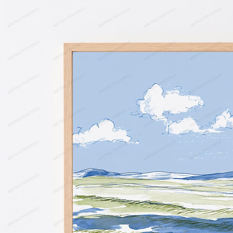 May include: A framed wall art print featuring a landscape illustration with a light blue sky, white clouds, and rolling green and blue fields. The artwork is enclosed in a light-colored wooden frame with a visible grain texture and clean edges.