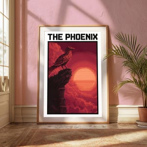Puede incluir: Una l&aacute;mina de arte mural rectangular enmarcada con una ilustraci&oacute;n estilo pixel art de un p&aacute;jaro posado en el borde de un acantilado frente a un gran sol naranja y nubes rojas. El texto THE PHOENIX aparece en letras negras en la parte superior.