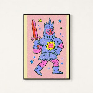 May include: A framed art print featuring a pink-skinned knight wearing blue armor and a crown, holding a red sword. The knight has a yellow sun emblem with a pink face on the chest. The background is textured pink with scattered blue and yellow stars.