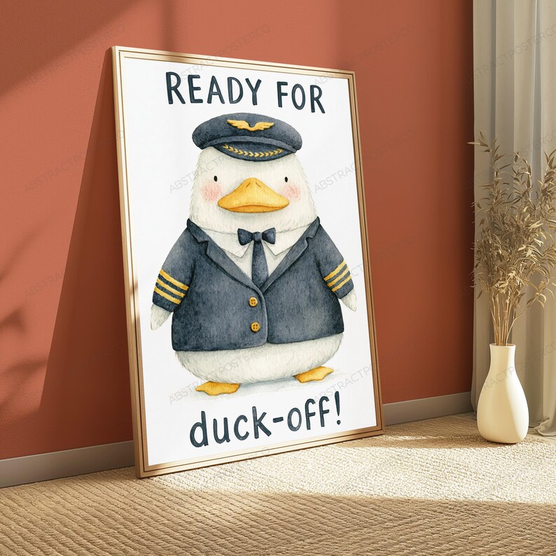 May include: A framed wall art print featuring a watercolor illustration of a white duck dressed as a pilot in a navy blue uniform with gold stripes, a black tie, and a pilot cap. The text reads READY FOR at the top and duck-off! at the bottom.