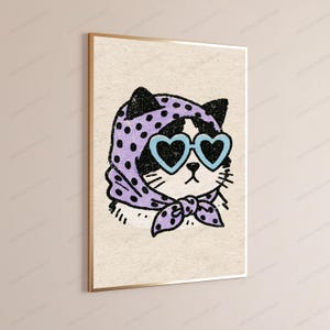 Pu&ograve; includere: Una stampa artistica da parete incorniciata raffigurante l'illustrazione di un gatto bianco e nero. Il gatto indossa un foulard viola chiaro a pois viola scuro e occhiali da sole a forma di cuore azzurri. L'opera ha un aspetto granuloso su sfondo beige.
