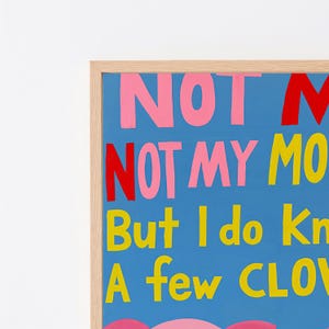 Puede incluir: Una pieza de arte mural enmarcada con fondo azul y texto pintado a mano en rosa, rojo y amarillo. El texto visible dice NOT M, NOT MY MO, But I do Kn, A few CLO. La obra est&aacute; encerrada en un marco de madera de tono claro con borde limpio.