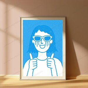 May include: A framed wall art print featuring a white line drawing of a person with short hair wearing sunglasses and giving a double thumbs-up gesture. The figure is set against a solid blue background with a textured, hand-drawn aesthetic.