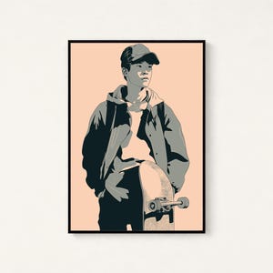 May include: A framed graphic art print featuring a stylized illustration of a person wearing a baseball cap and a hooded jacket, standing while holding a skateboard. The artwork uses a palette of dark gray, light gray, and a soft peach background.