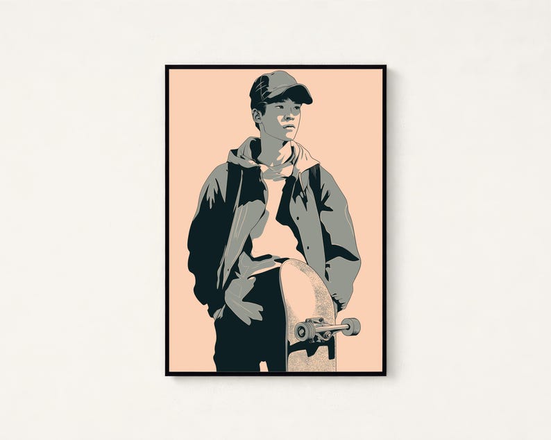 May include: A framed graphic art print featuring a stylized illustration of a person wearing a baseball cap and a hooded jacket, standing while holding a skateboard. The artwork uses a palette of dark gray, light gray, and a soft peach background.