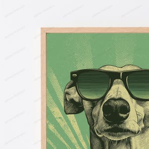 May include: A framed wall art print featuring a stylized illustration of a dog wearing large black sunglasses. The artwork uses a green background with a halftone dot pattern and light rays, rendered in a detailed, etched line art style.