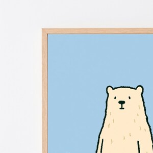 May include: A framed wall art print featuring a stylized illustration of a cream-colored bear against a solid light blue background. The bear has simple black facial features and a textured appearance, enclosed within a light-toned wooden frame.