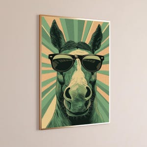 K&ouml;nnte beinhalten: Ein gerahmter Wandkunstdruck mit einer stilisierten Illustration eines Pferdes, das eine schwarze Sonnenbrille tr&auml;gt. Das Pferd ist in Gr&uuml;n- und Cremet&ouml;nen gehalten und vor einem Hintergrund aus strahlenden Sonnenstrahlen in Gr&uuml;n und Beige.