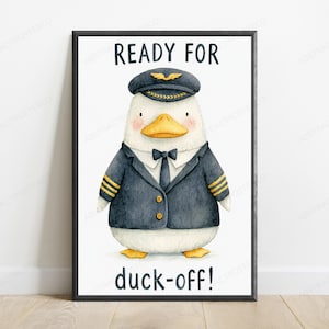 May include: A framed wall art print featuring a white duck dressed as a pilot in a dark blue uniform with gold stripes, a black tie, and a pilot cap. The text READY FOR is printed above the duck, and the text duck-off! is printed below the duck.