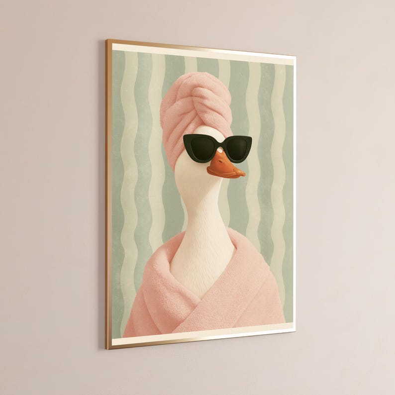 Puede incluir: Una l&aacute;mina de arte mural enmarcada que muestra un ganso blanco con una toalla rosa envuelta alrededor de la cabeza, un albornoz rosa a juego y gafas de sol negras. El fondo presenta rayas verticales onduladas en tonos verde claro y crema.