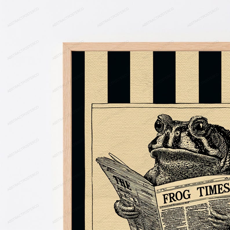 May include: A framed wall art print featuring a black and white illustration of a toad reading a newspaper titled THE FROG TIMES. The background consists of vertical black and beige stripes, and the frame is made of light-colored wood.