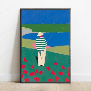 Op de afbeelding: Een ingelijste kunstdruk met een persoon in een strooien hoed en een groen-wit gestreept shirt in een veld met rode bloemen. De sc&egrave;ne bevat een blauw wateroppervlak, groene heuvels en een helderblauwe lucht, weergegeven in een vlakke schilderstijl.