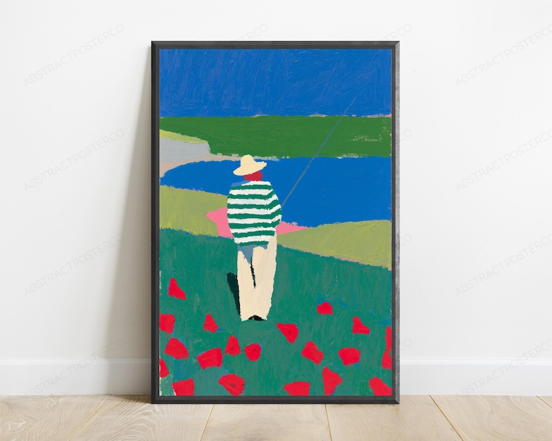 Op de afbeelding: Een ingelijste kunstdruk met een persoon in een strooien hoed en een groen-wit gestreept shirt in een veld met rode bloemen. De sc&egrave;ne bevat een blauw wateroppervlak, groene heuvels en een helderblauwe lucht, weergegeven in een vlakke schilderstijl.