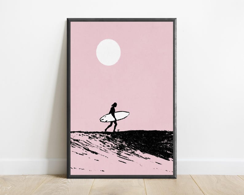 K&ouml;nnte beinhalten: Ein gerahmter Wandkunstdruck mit der schwarzen Silhouette einer Person, die ein Surfbrett &uuml;ber eine texturierte schwarze Welle tr&auml;gt, vor einem einfarbigen hellrosa Hintergrund mit einer wei&szlig;en kreisf&ouml;rmigen Sonne in der oberen Mitte.