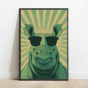 May include: A framed wall art print featuring a green rhinoceros wearing black sunglasses. The background consists of a radiating sunburst pattern in alternating shades of light green and tan, rendered with a dotted halftone texture effect.