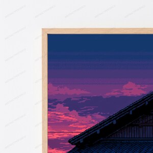 May include: A framed pixel art print featuring a dark silhouette of a traditional tiled roof against a vibrant sunset sky. The sky transitions from deep blue at the top to shades of purple and bright pink near the horizon, all encased in a light wood frame.