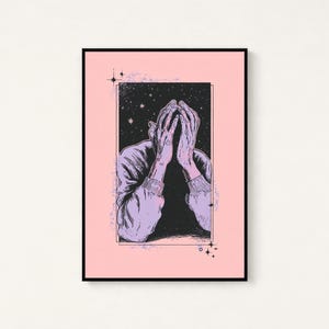 May include: A framed art print featuring a black and white illustration of a person with their hands covering their face. The figure is set against a dark, starry background within a rectangular border, all centered on a solid light pink background.