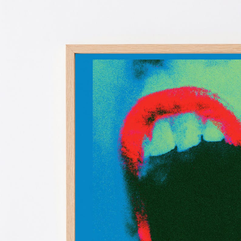 Puede incluir: Una impresi&oacute;n de arte mural enmarcada que presenta un gr&aacute;fico estilizado de alto contraste de una boca abierta con dientes visibles. La obra utiliza una paleta de colores vibrantes en rojo brillante, verde oscuro y azul el&eacute;ctrico, en un marco de madera clara.