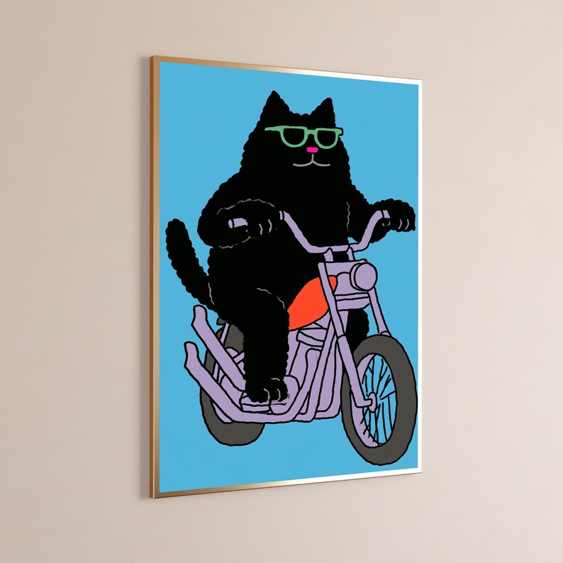 以下が含まれることがあります： ピンクの鼻とライトグリーンのサングラスをかけた黒猫が描かれた額装アートプリント。明るいオレンジ色のガソリンタンクを備えたライトパープルのオートバイに乗っており、背景は鮮やかなライトブルーの無地となっている。