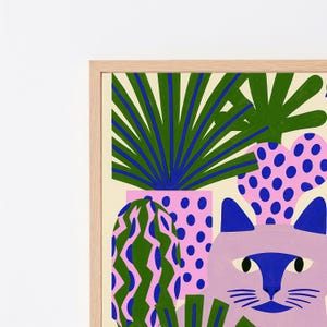 May include: A framed art print featuring a light purple cat with a dark blue face mask, surrounded by stylized potted plants. The plants include a green palm, a pink cactus with blue dots, and a green cactus with pink wavy vertical stripes.