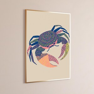 May include: A framed wall art print featuring a stylized crab illustration on a light beige background. The crab is rendered in navy blue, pink, and yellow, utilizing a mix of dotted, stippled, and striped patterns across its shell and legs.