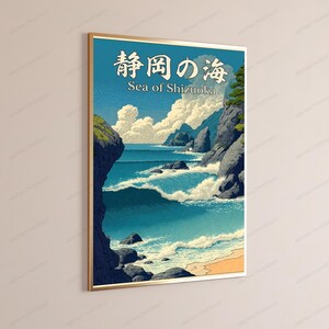Puede incluir: Una impresi&oacute;n de arte mural vertical enmarcada que muestra un paisaje costero con acantilados rocosos, olas azules del oc&eacute;ano y una playa de arena. El texto en la parte superior dice "静岡の海" y "Sea of Shizuoka" en letras blancas sobre un cielo azul.