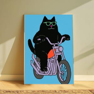 以下が含まれることがあります： ピンクの鼻と鮮やかな緑色のサングラスをかけた黒猫が描かれた長方形のアートプリント。猫は、鮮やかなオレンジ色のガソリンタンクを備えた薄紫色のオートバイに乗っており、背景は鮮やかな水色で塗りつぶされています。