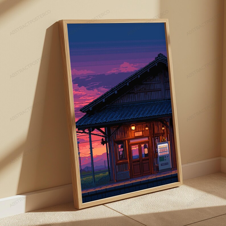 May include: A framed vertical art print featuring a pixel art style illustration of a train station building at sunset. The scene displays a dark wooden structure with a tiled roof, warm glowing lights, and a vending machine under a purple sky.