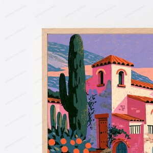 May include: A framed art print featuring a Mediterranean-style building with pink walls and a terracotta roof, surrounded by tall dark green cacti and a citrus tree with orange fruit. The background shows purple mountains under a soft sky.