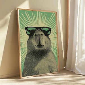 Peut inclure: Une impression d'art mural encadr&eacute;e repr&eacute;sentant une illustration monochrome d'un capybara portant des lunettes de soleil noires. Le capybara est centr&eacute; sur un fond vert clair avec des lignes de rayons de soleil blanches rayonnant vers l'ext&eacute;rieur.