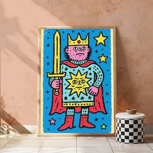 May include: A framed art print featuring a stylized illustration of a king with a pink face, wearing a yellow crown and a red cape. The figure holds a yellow sword against a blue background filled with yellow stars and a central sun emblem.