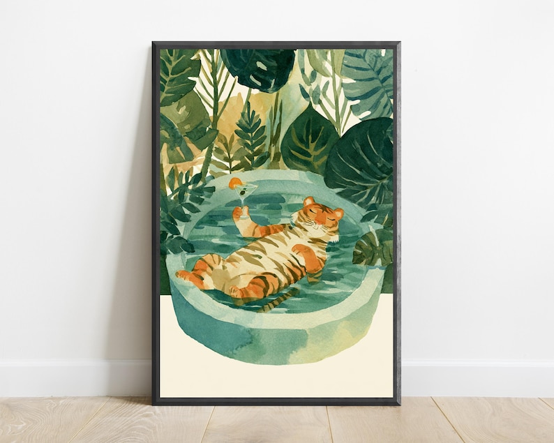 Peut inclure: Une impression d'art mural encadr&eacute;e repr&eacute;sentant un tigre aux rayures orange et noires flottant sur le dos dans une piscine ronde bleu clair. Le tigre tient un petit verre &agrave; cocktail avec une tranche d'orange. Entour&eacute; de feuillage vert fonc&eacute;.