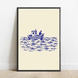 May include: A framed wall art print featuring a blue ink illustration on a cream background. The artwork depicts a small boat with a cabin floating on stylised, choppy ocean waves, with a figure visible inside the boat steering the vessel.