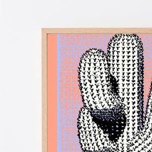 May include: A framed wall art print featuring a pixelated cactus illustration in black and white against a light blue and peach background with a maze-like pattern. The artwork is encased in a light-toned wooden frame with a clean, simple border.