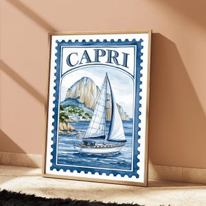 May include: A rectangular wall art print designed like a postage stamp with a blue scalloped border. The illustration features a white sailboat on blue water with a large rocky mountain and coastal buildings in the background. The word CAPRI is printed in large blue serif letters at the top of the frame.