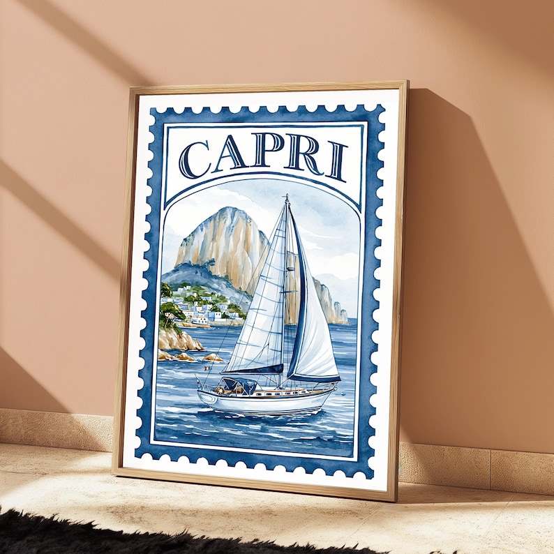 May include: A rectangular wall art print designed like a postage stamp with a blue scalloped border. The illustration features a white sailboat on blue water with a large rocky mountain and coastal buildings in the background. The word CAPRI is printed in large blue serif letters at the top of the frame.