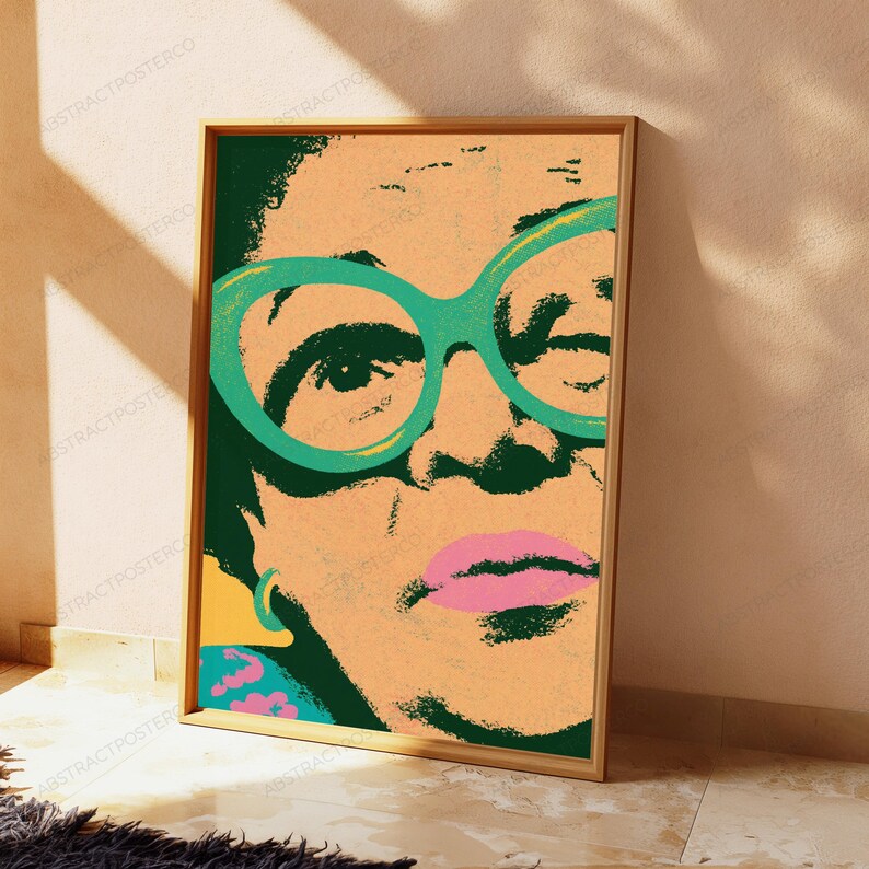 May include: A rectangular wall art print featuring a stylized, high-contrast portrait of a person wearing large, bright teal glasses. The artwork uses a bold color palette of peach, dark green, and pink, with a textured, screen-printed aesthetic.