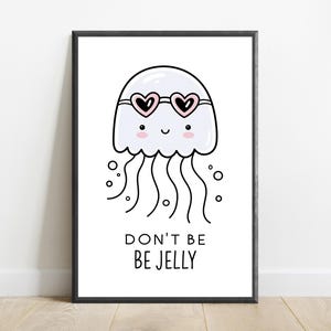 May include: A framed wall art print featuring a white cartoon jellyfish with pink cheeks and heart-shaped sunglasses. The jellyfish has long wavy tentacles and small bubbles around it. Below the illustration, the text reads DON'T BE BE JELLY.