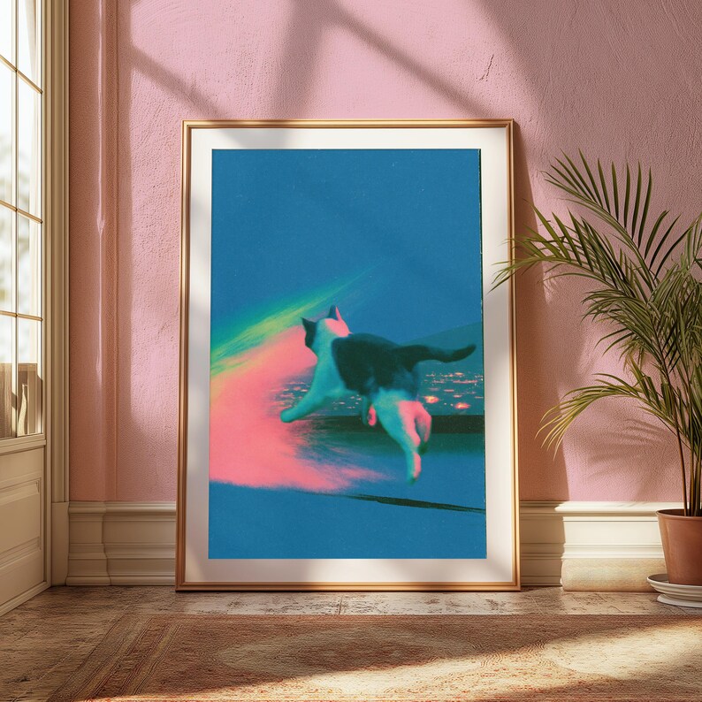 May include: A framed wall art print featuring a black and white cat leaping across a dark blue background. The cat is surrounded by a vibrant, glowing pink and green light effect that streaks across the composition, creating a surreal, dreamlike atmosphere.