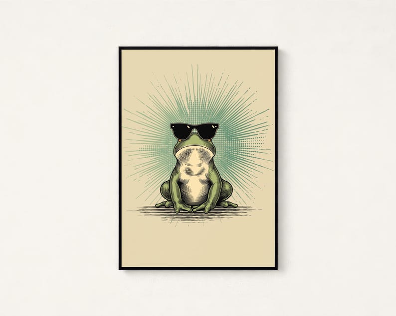 May include: A framed wall art print featuring a green frog wearing black sunglasses. The frog is centered against a light beige background with a radiating teal sunburst pattern emanating from behind its head, enclosed in a thin black frame.