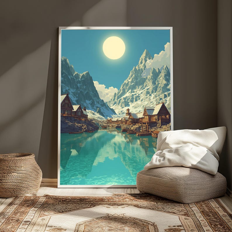 Puede incluir: Una impresi&oacute;n art&iacute;stica enmarcada representa una serena escena de un pueblo de monta&ntilde;a. Picos nevados rodean un lago turquesa, reflejando el sol. Edificios de madera bordean la orilla, creando un paisaje pintoresco. La obra de arte se exhibe en una habitaci&oacute;n con una cesta tejida, una alfombra y un puf.
