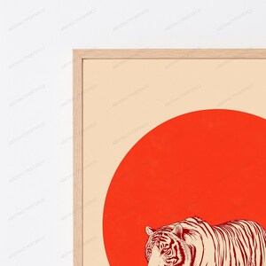 May include: A framed wall art print featuring a large, solid red circle centred on a light beige background. In the foreground, a detailed illustration of a tiger with dark red stripes is positioned at the bottom, partially overlapping the red circle.